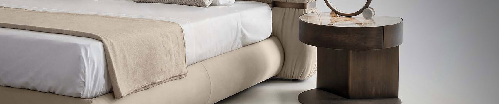 Round wooden bedside table with marble top beside bed