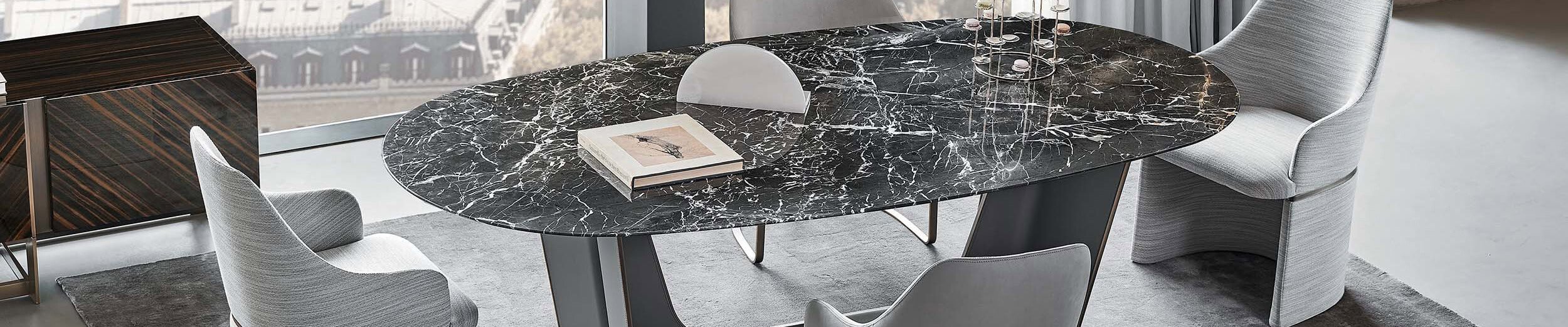 Oval black marble dining table with gray upholstered chairs