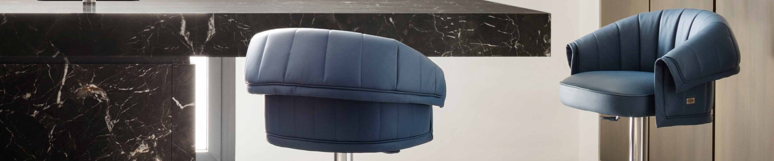 Blue upholstered swivel bar stools with metal base near marble counter